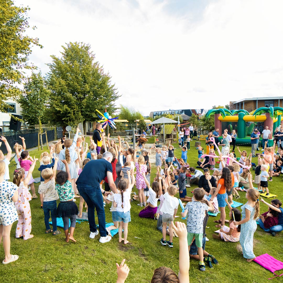 In de tuin van de locatie Bereboot in Helmond doet een grote groep kinderen mee met een goochelaar