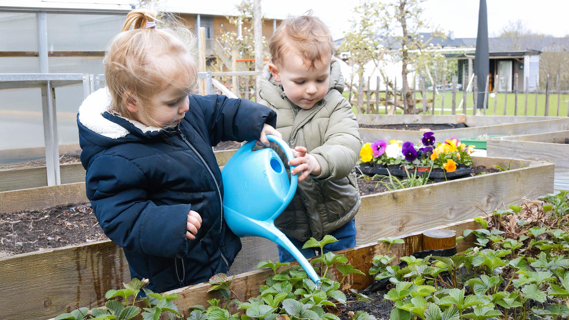 Twee kindjes geven plantjes water op locatie Helmond van Kids Lodge