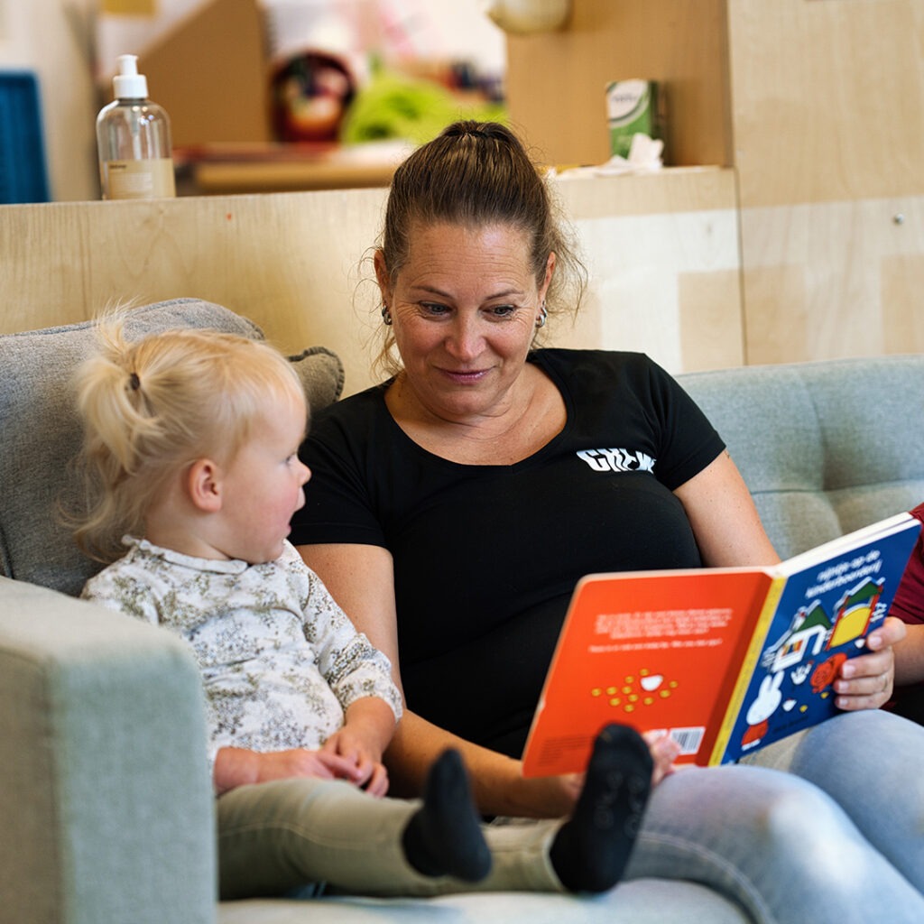 Pedagogisch medewerker van Kids Lodge leest voor aan peuter