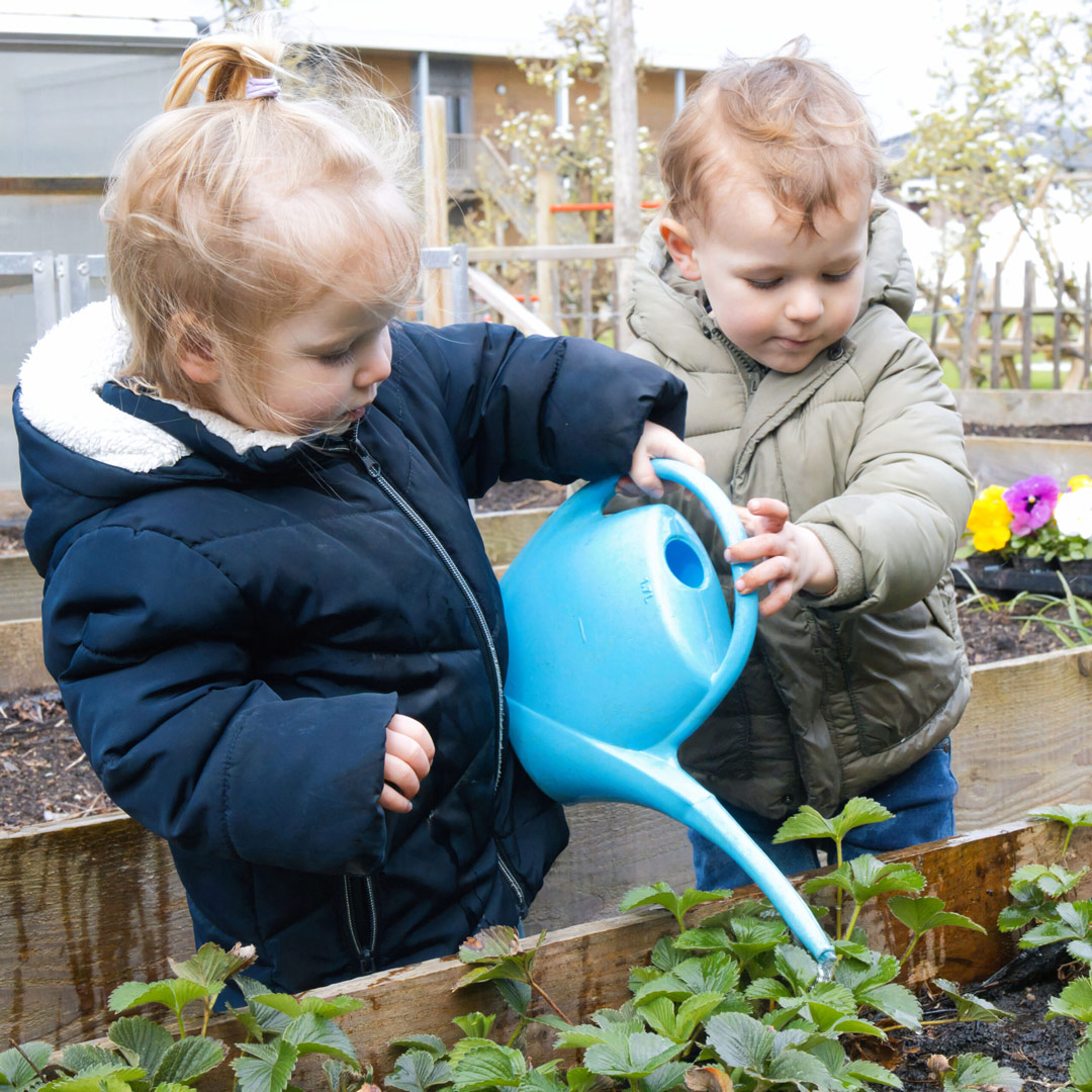 Twee kindjes geven plantjes water op locatie Helmond van Kids Lodge