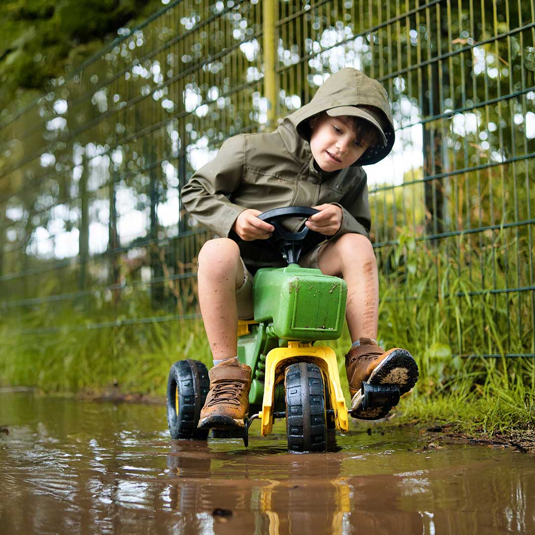 Kinderen spelen buiten en steken hun handen in de lucht bij Kids Lodge