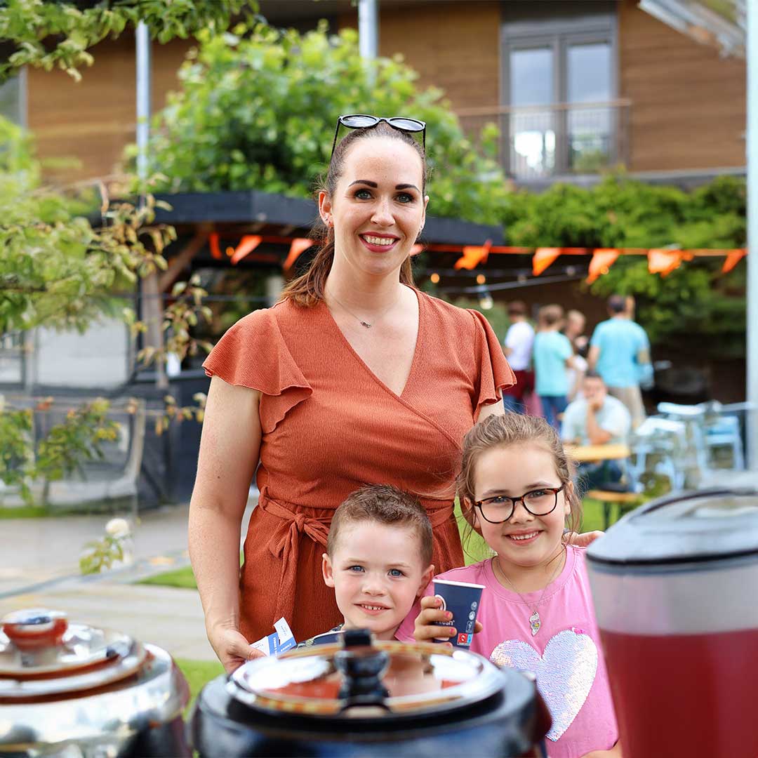 Twee kinderen en hun moeder poseren voor de camera tijdens een Kids Lodge event
