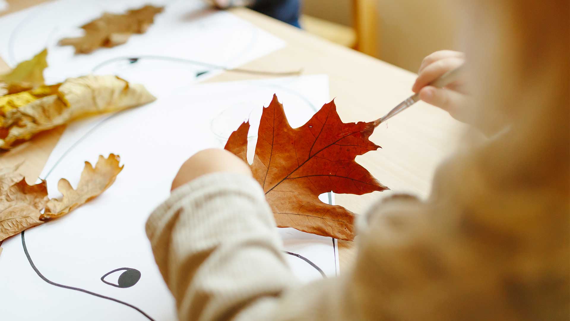 Een kind verft een herfstblad rood op de locatie Midlandia in Bunnik