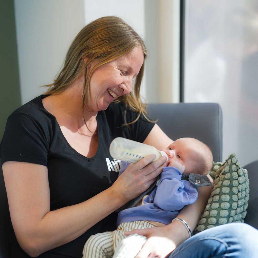 Pedagogisch medewerker van Kids Lodge geeft baby een flesje