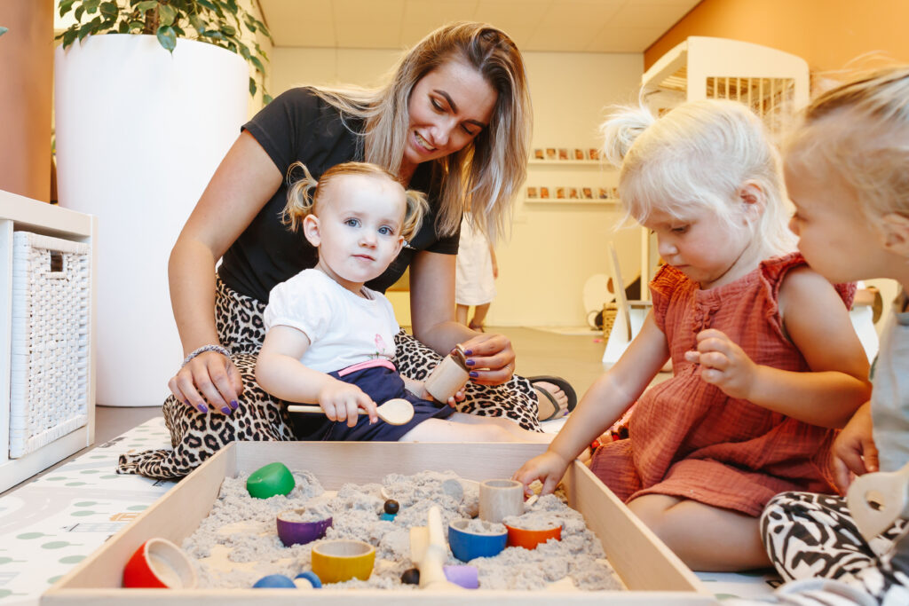 Kinderen spelen binnen met zand met een Kids Lodge medewerker