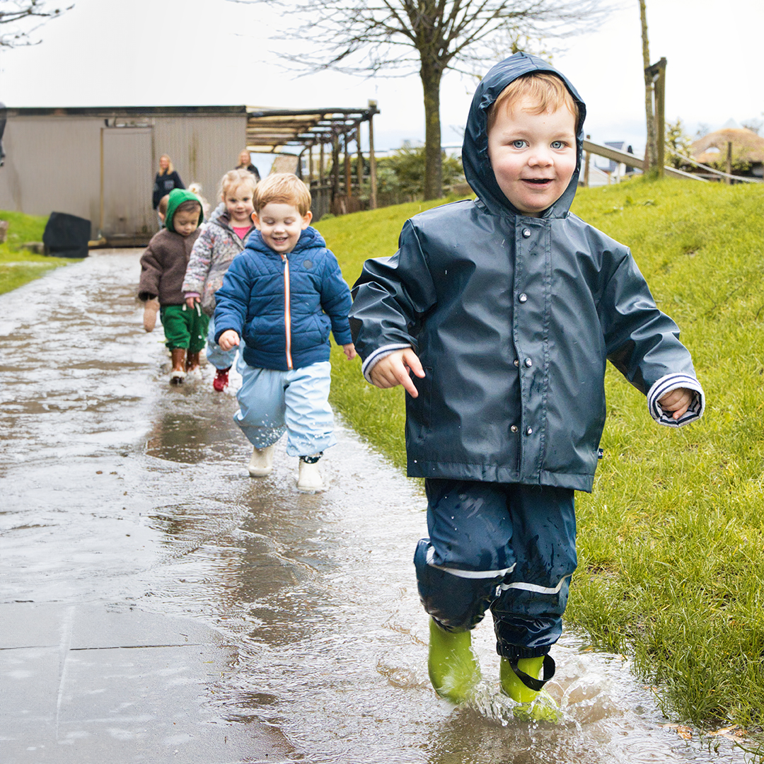 Buitenspelen bij kinderopvang KidsLodge, kinderen stappen door plassen