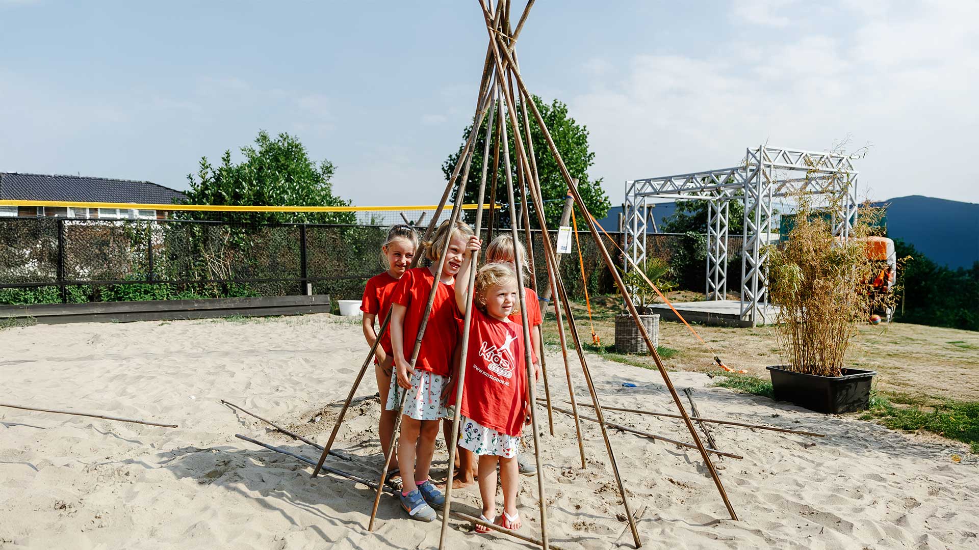 Kinderen bouwen een tipi met lange stokken