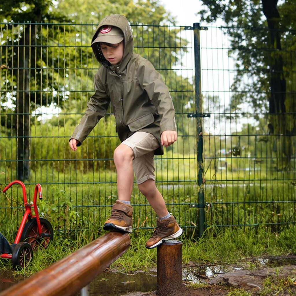 Jongen loopt over een houten balk bij outdoor activiteit van Kids Lodge