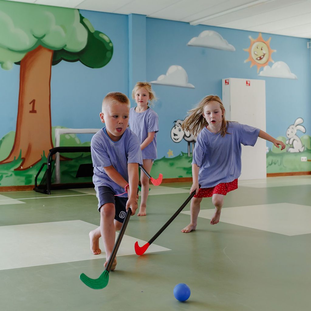 Kinderen spelen hockey in de gymzaal