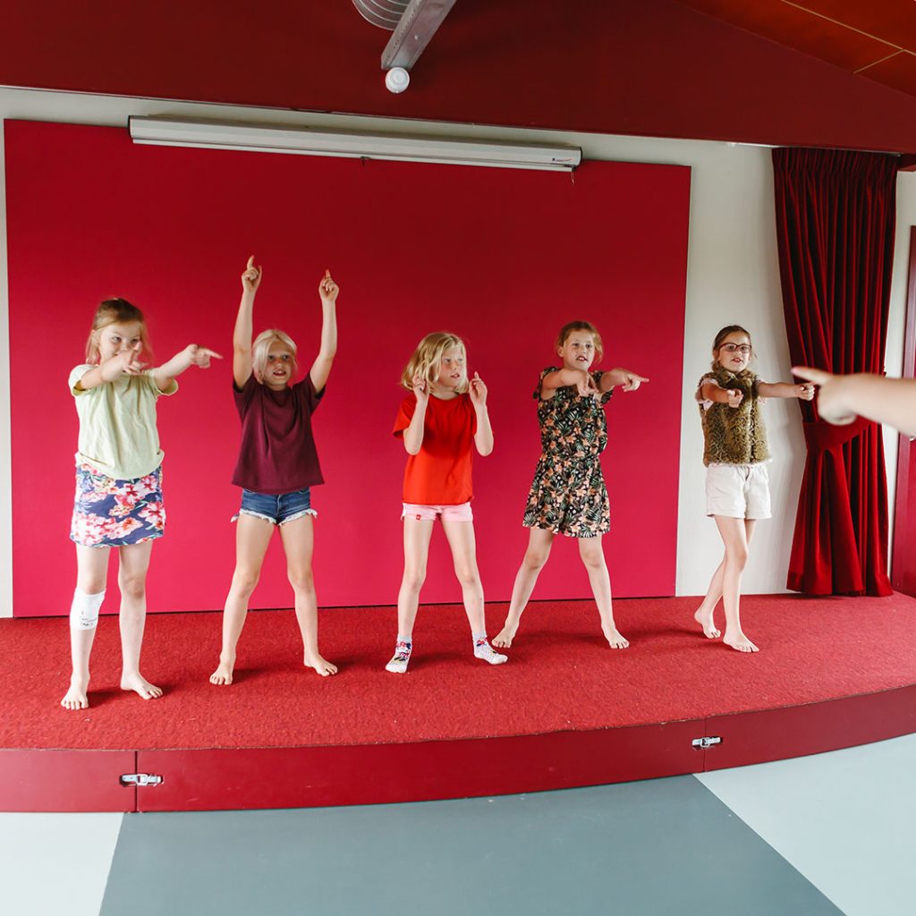 Vijf kinderen staan op een podium en oefenen voor een dansvoorstelling aan de locatie Tuibrug