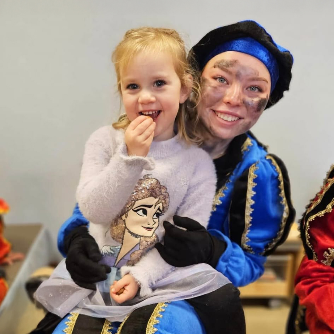 Een blij meisje poseert met Piet voor de foto tijdens een Sinterklaasfeest