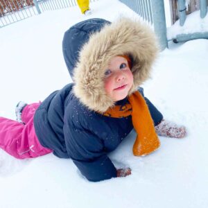 Peuter speelt buiten in de sneeuw bij Kids Lodge