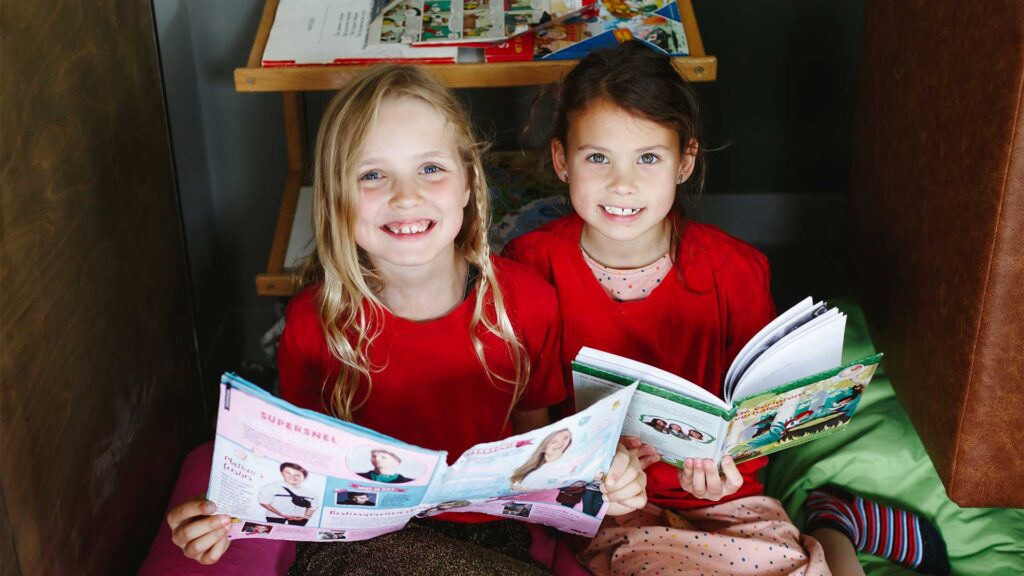 Twee kinderen lezen een boek bij de bso van Kids Lodge