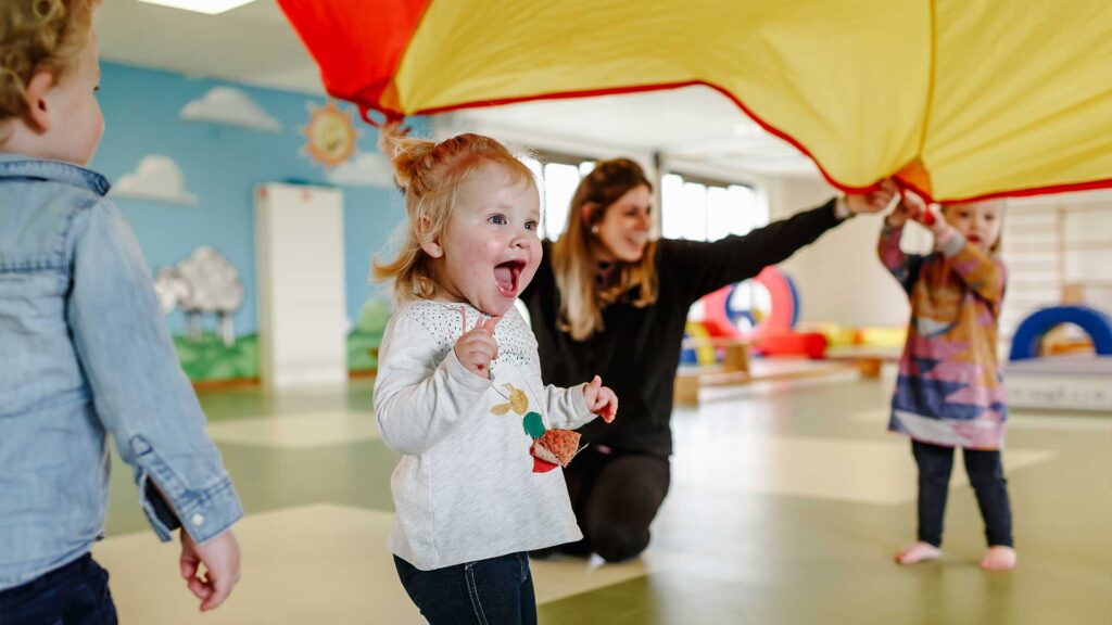 Peuter bij Kids Lodge loopt blij onder een doek door